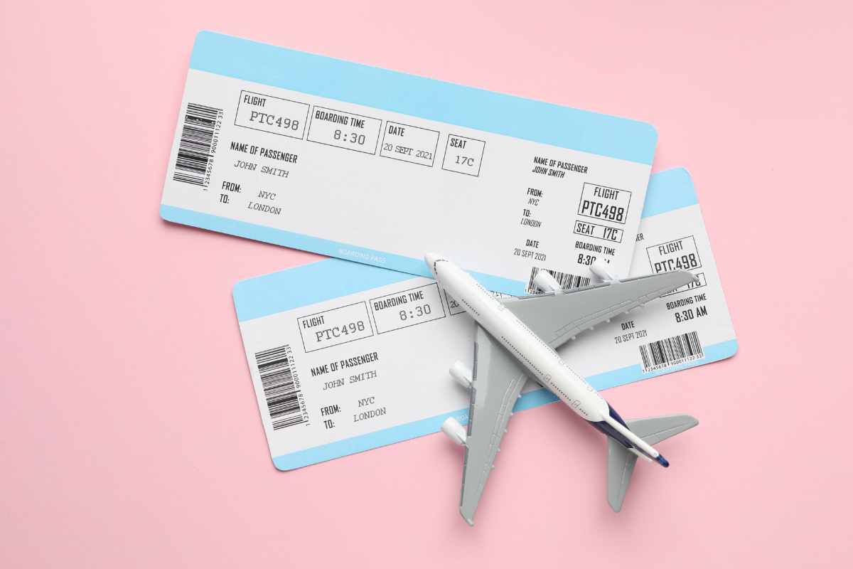 biglietti aerei sotto un fermacarte a forma di aeroplano