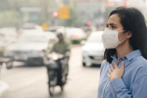 donna con la mascherina in una città inquinata