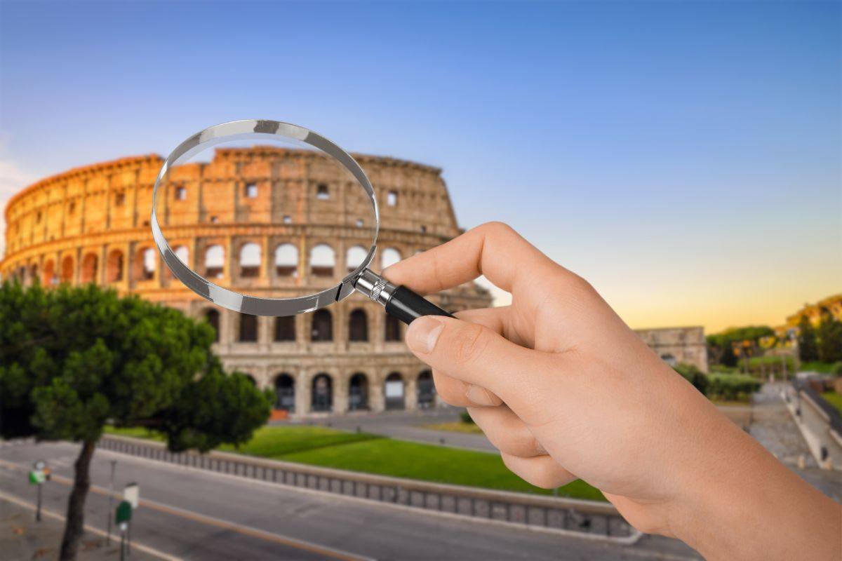 colosseo e mano che tiene lente ingrandimento