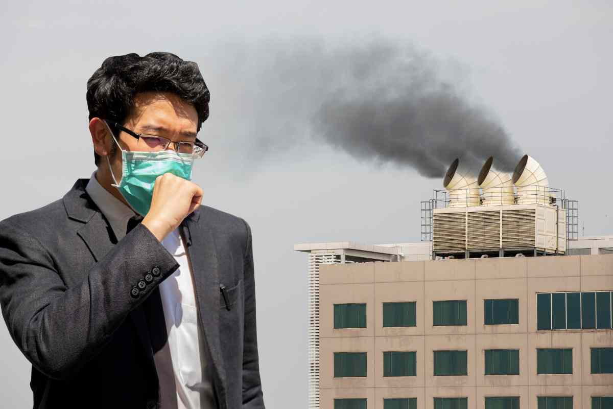 persona tossisce con mascherina davanti a una fabbrica