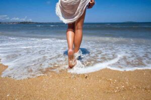 donna in spiaggia con i piedi al mare