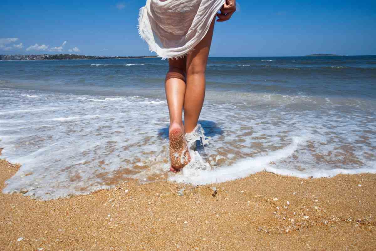 donna in spiaggia con i piedi al mare